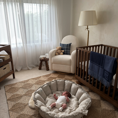 Nursery room with crib, chair, and baby in a basket.